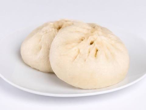 Freshly steamed pork buns served on a white plate