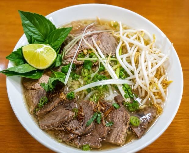 Bowl of house special beef pho with rare beef, bean sprouts, Thai basil and lime